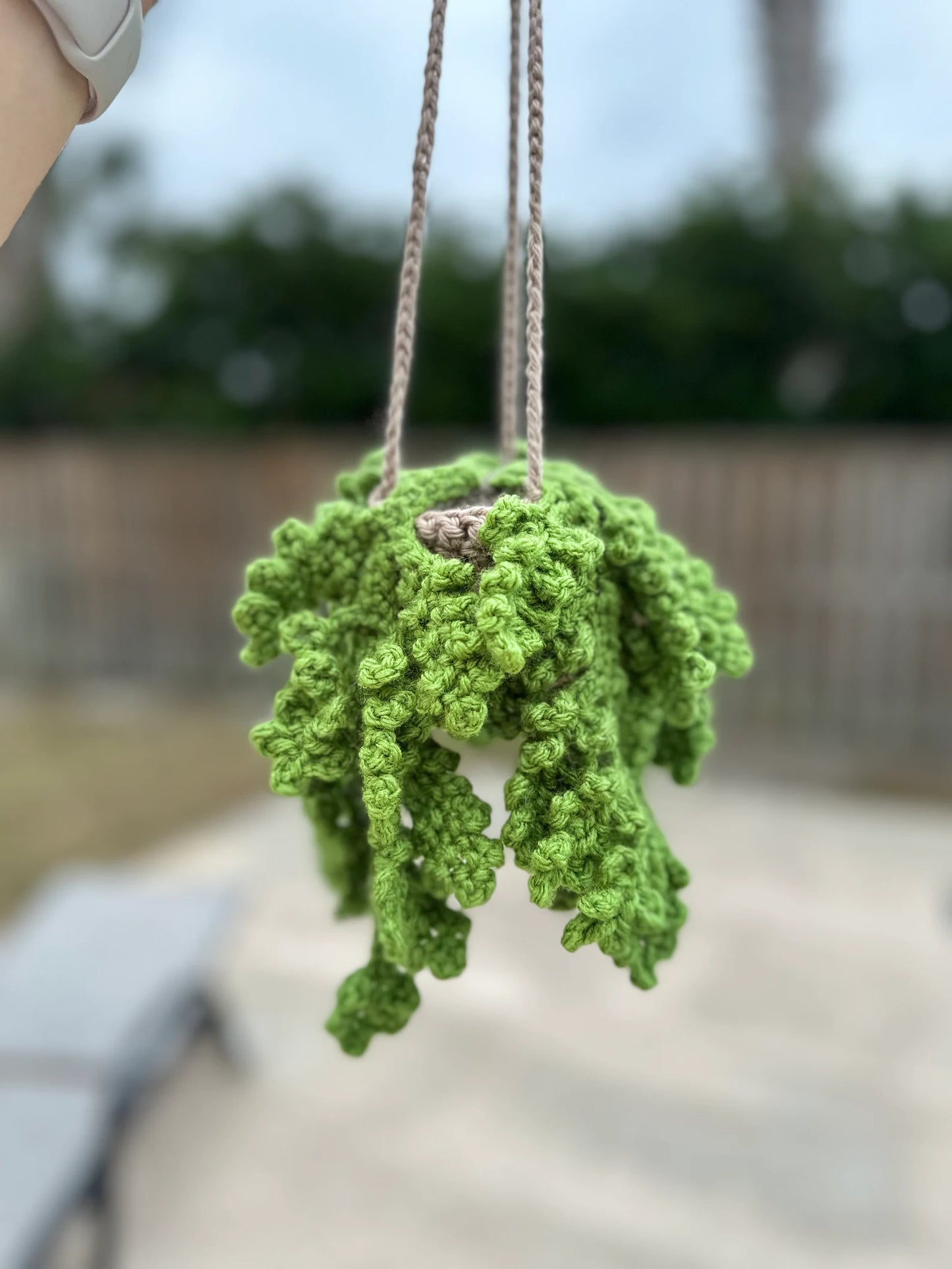 Finished hanging crochet fern plant held outdoors
