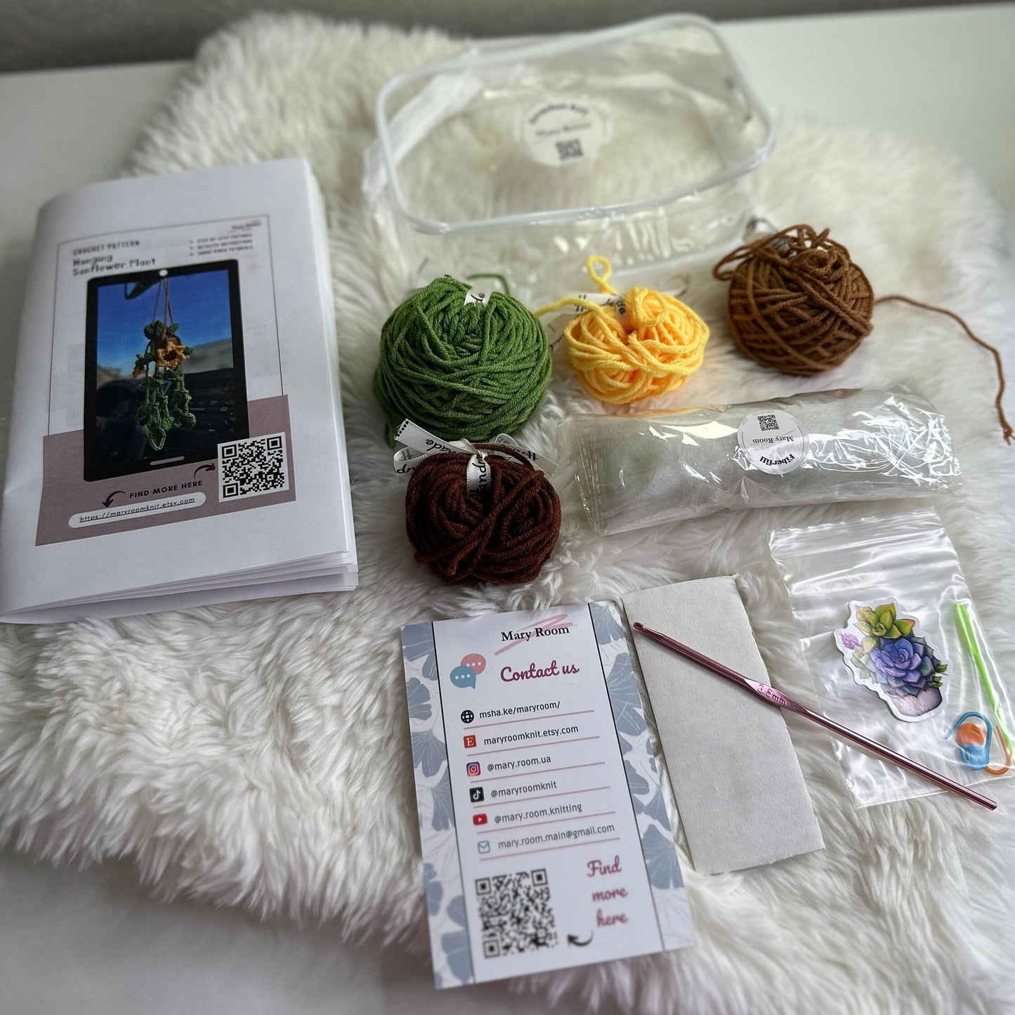 Flat lay of sunflower crochet kit components: yarn balls, cardboard, stitch marker and pattern