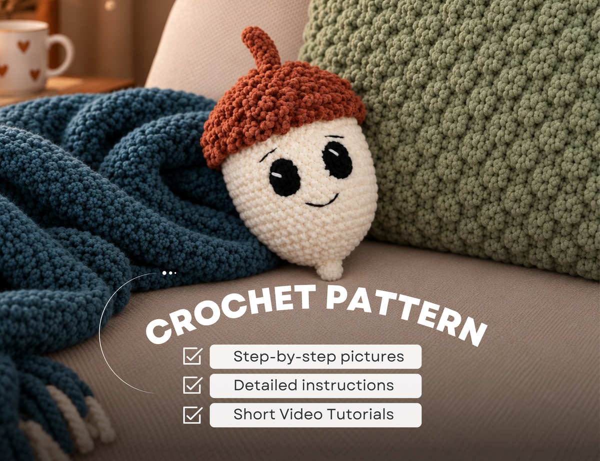 A crocheted acorn-shaped plush toy with a cream body, black embroidered eyes and smile, and a brown acorn cap, resting on a couch beside a blue blanket and green pillow. Large overlaid text reads 'CROCHET PATTERN' with bullet points for step-by-step pictures, detailed instructions, and short video tutorials.
