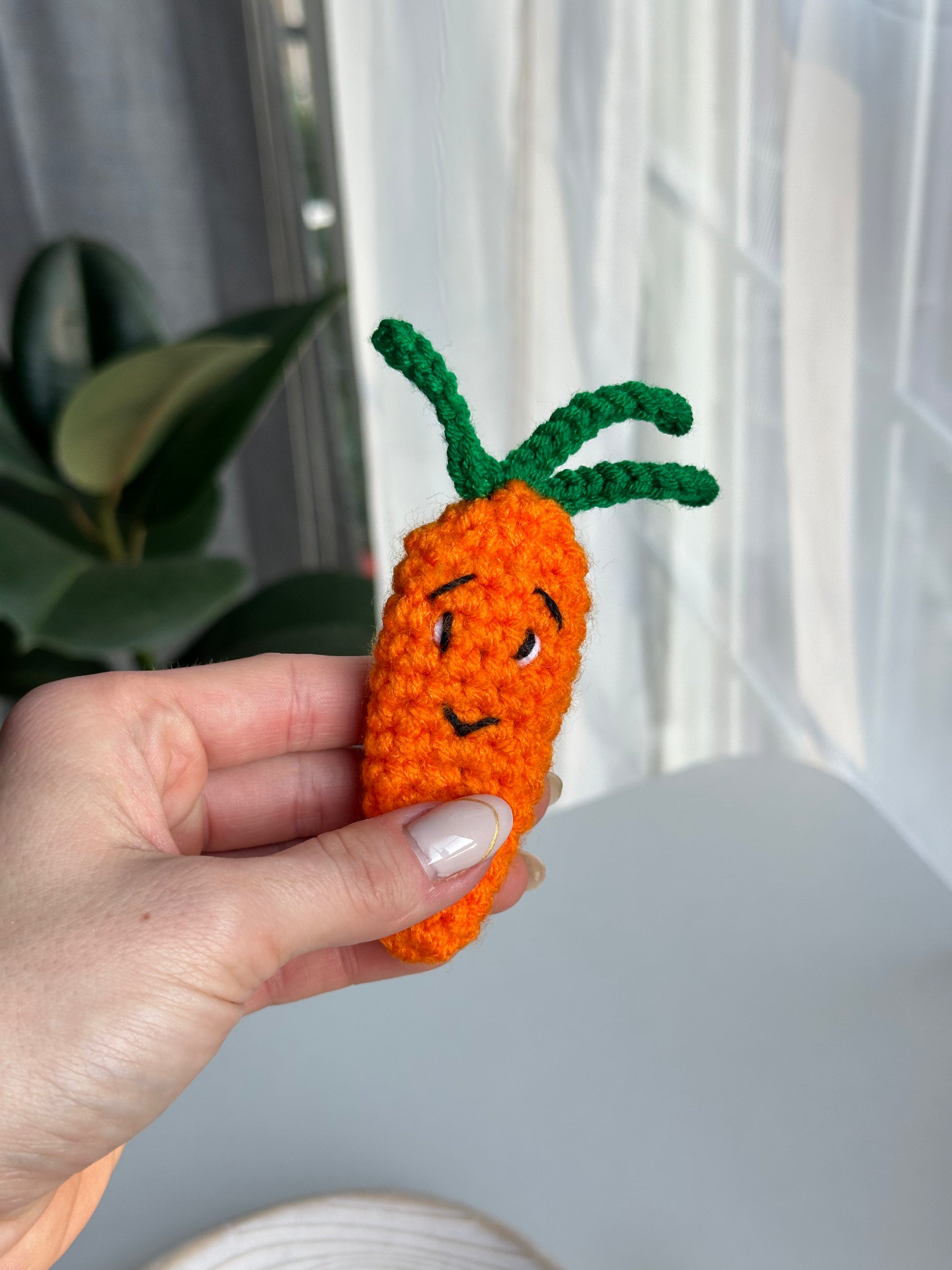 Hand holding crocheted acrylic carrot with hair clip from acrylic yarn