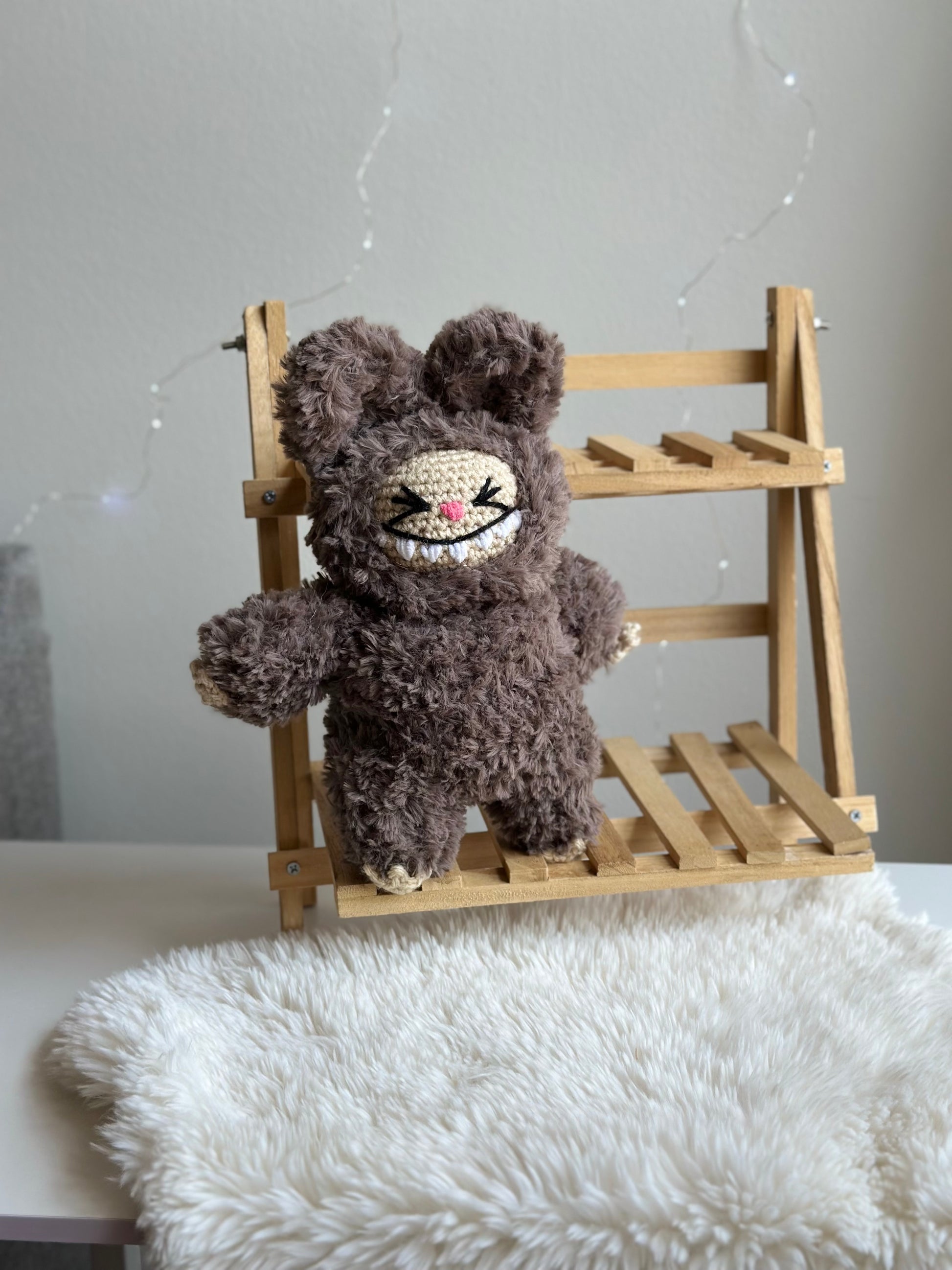 Brown faux fur Labubu plushie sitting alone on a mini wooden bench, highlighting its fuzzy texture.

