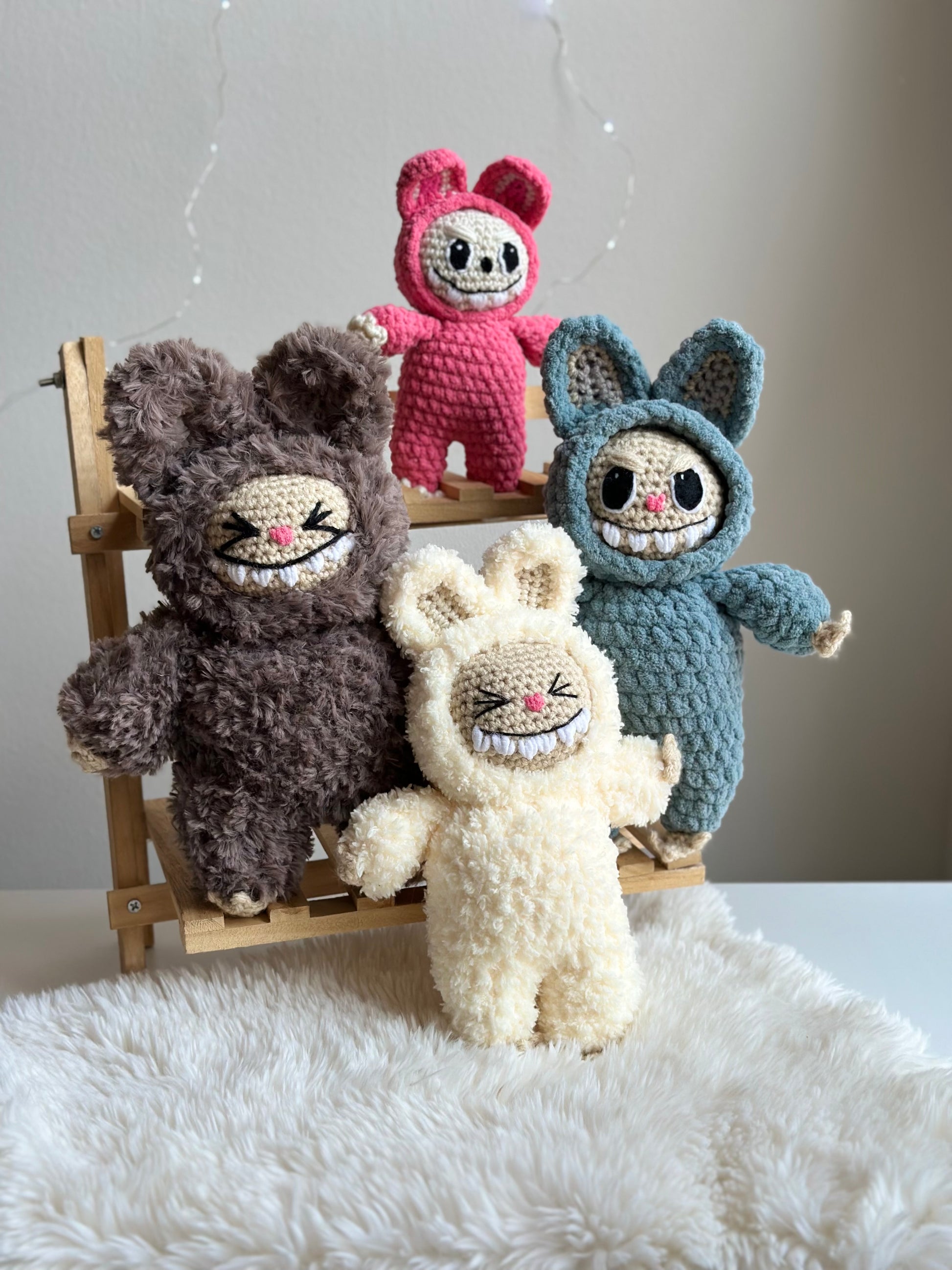 Group shot of three Labubus made from sherpa, classic yarn, and plushie yarn sitting on faux fur background. Crochet pattern