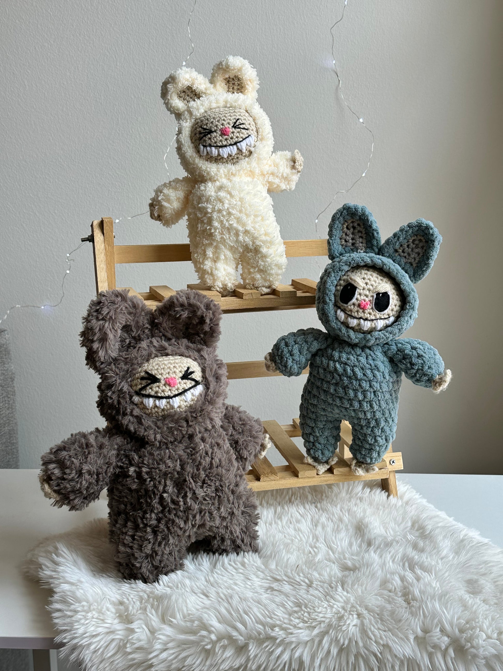 Group shot of three Labubus made from sherpa, classic yarn, and plushie yarn sitting on faux fur background.