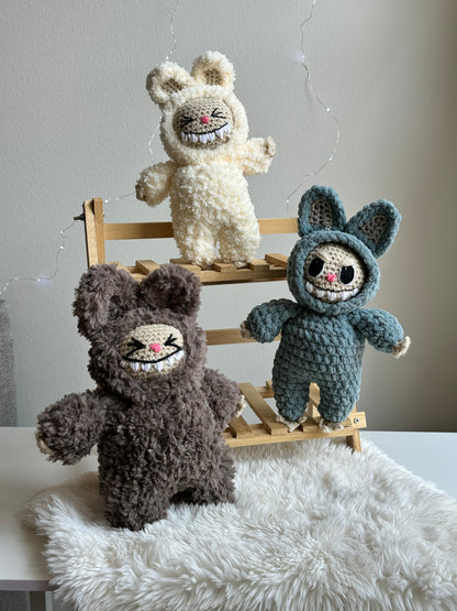 Group shot of three Labubus made from sherpa, classic yarn, and plushie yarn sitting on faux fur background.