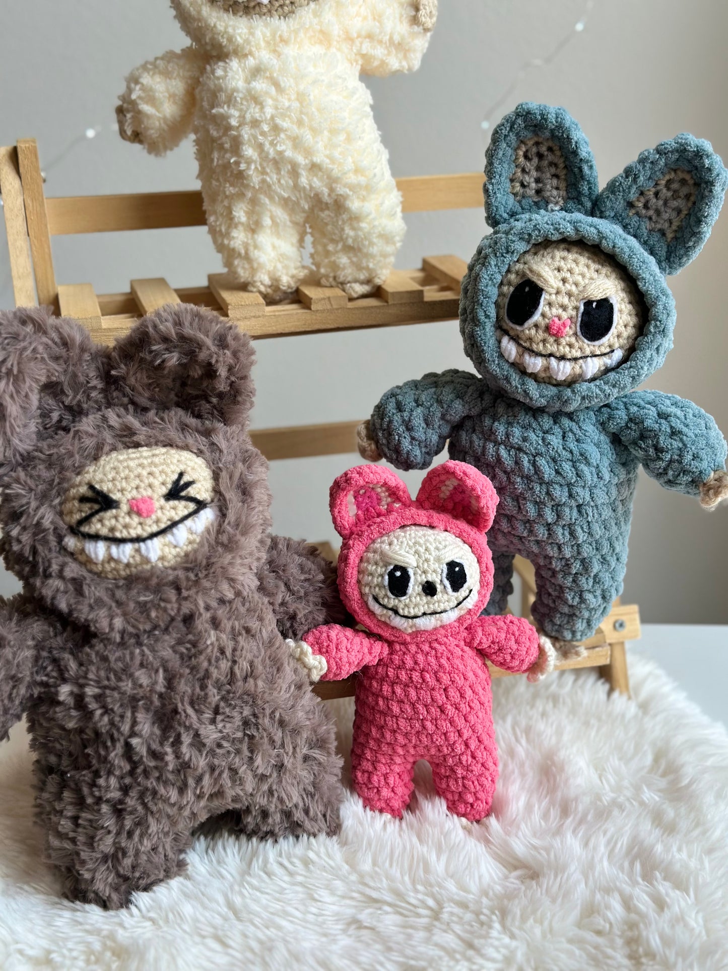 Final trio of crocheted Labubus in varied yarns: brown fluffy fur, pink standard yarn, and blue plushie. Crochet Pattern