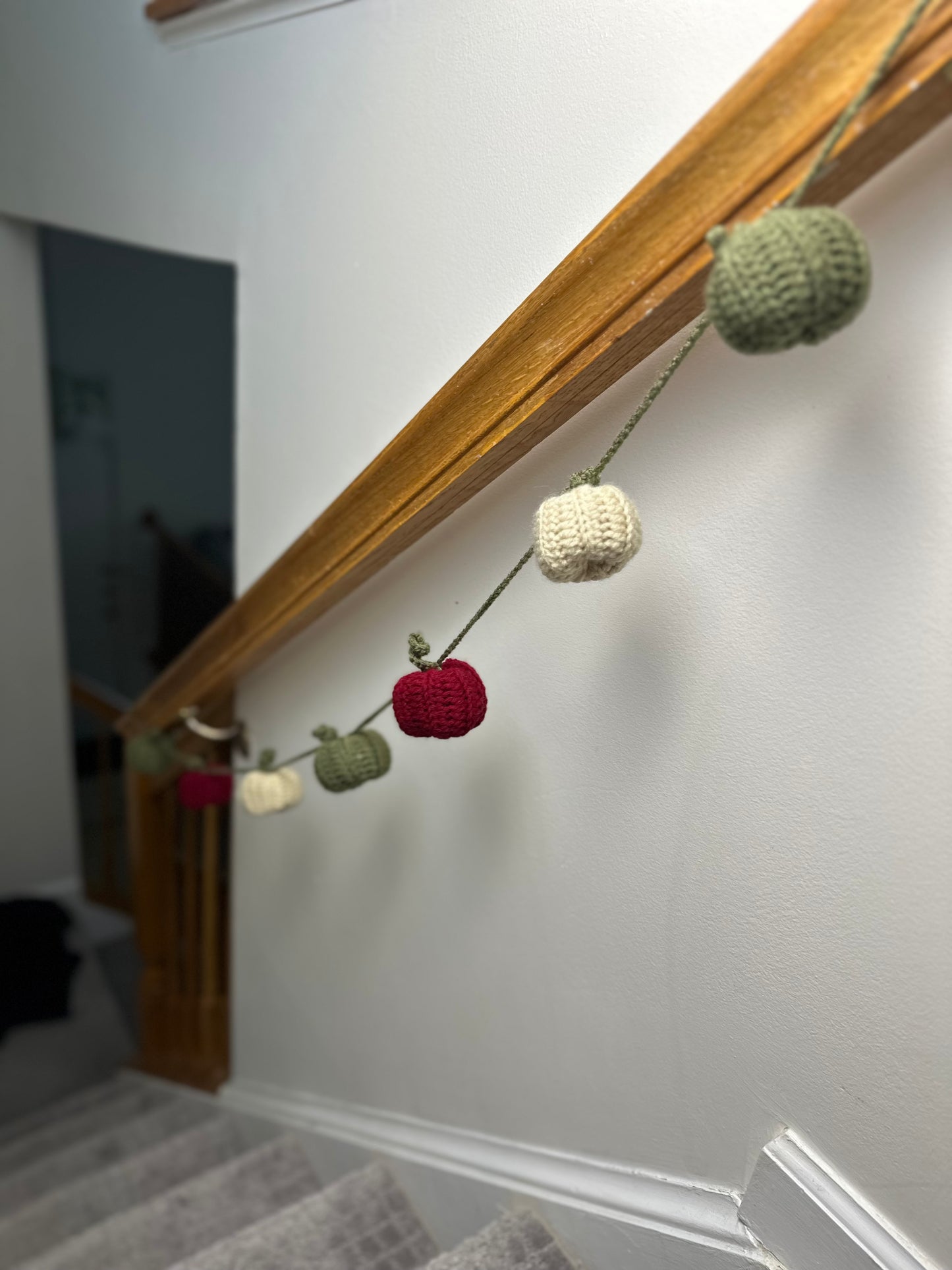 Decorative garland with crocheted pumpkins hanging on a stair railing.
