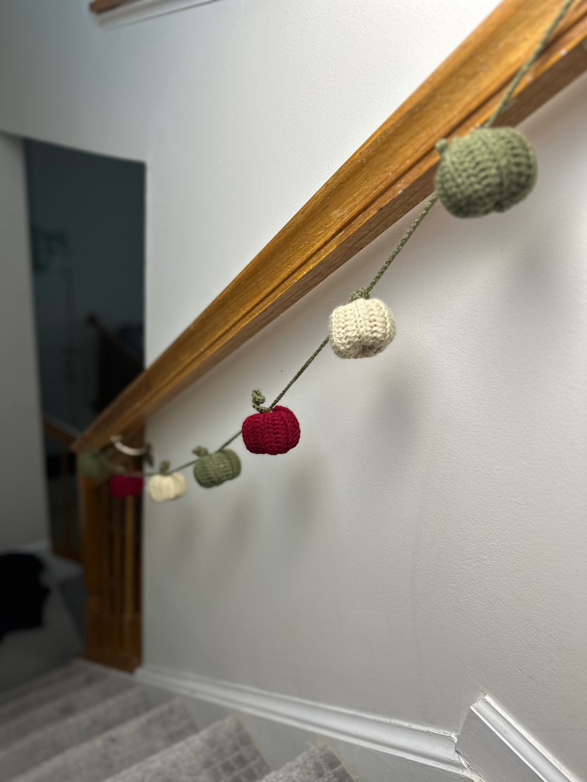 Decorative garland with crocheted pumpkins hanging on a stair railing.