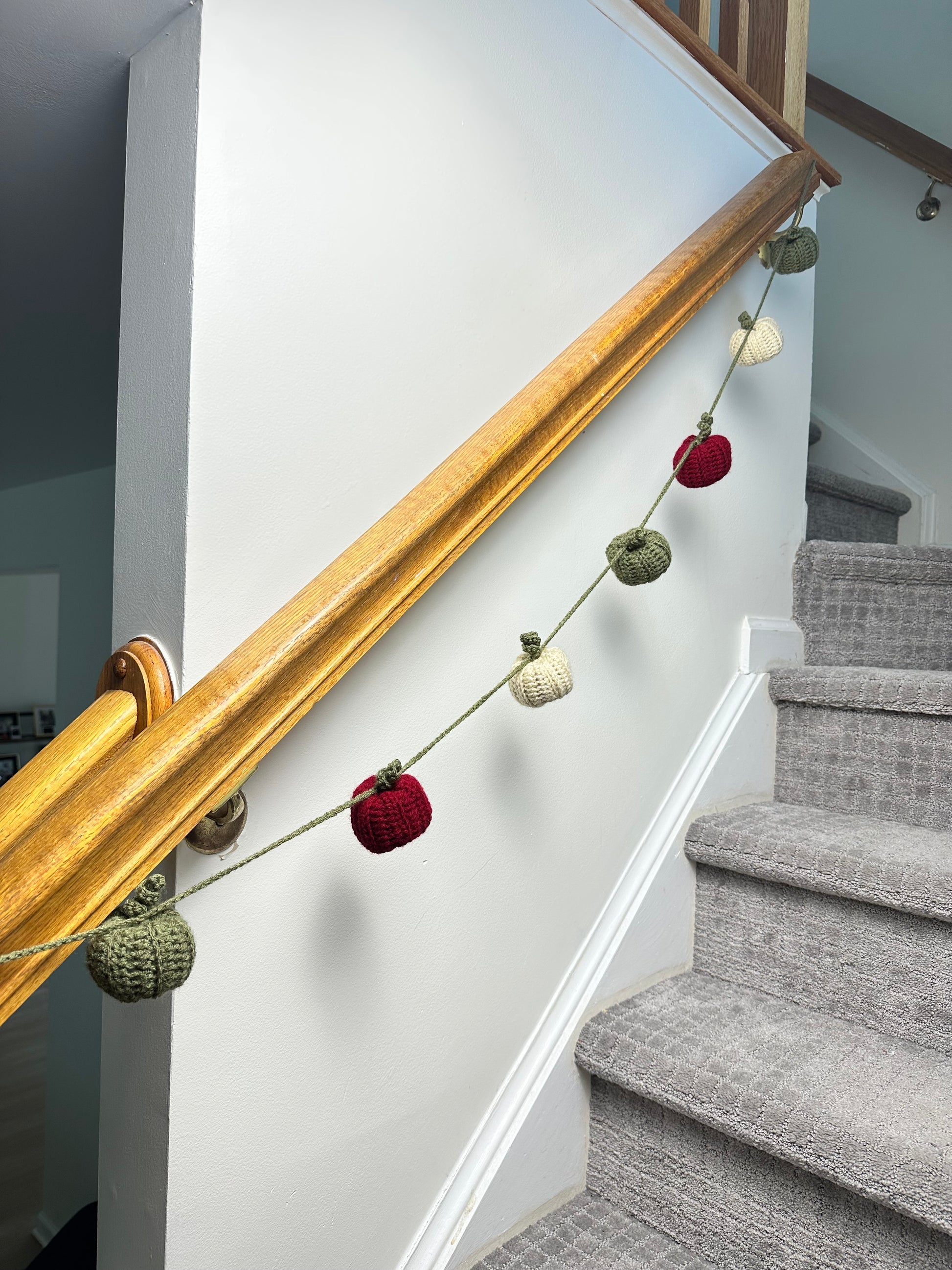 Decorative crochet garland with colorful pumpkins on a staircase railing.
