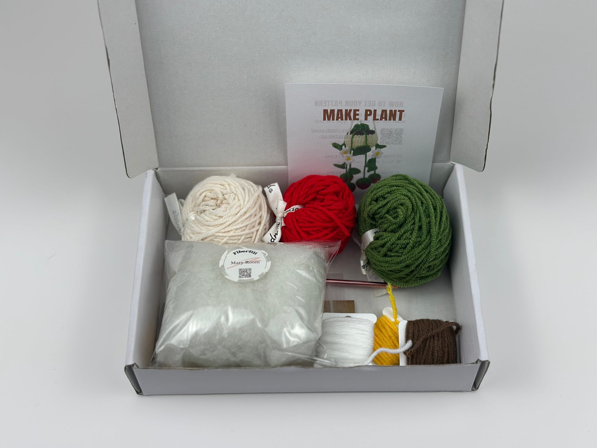 Crochet KIT DIY Box containing yarn balls, tools and material with a 'MAKE PLANT' pattern access card on a white background