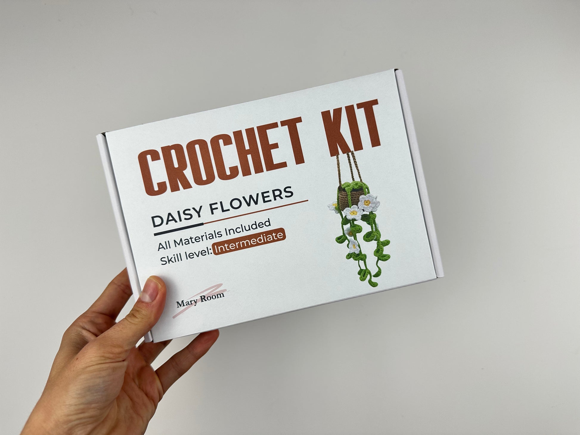 DIY crochet hanging plant kit featuring soft green vines and white daisy flowers