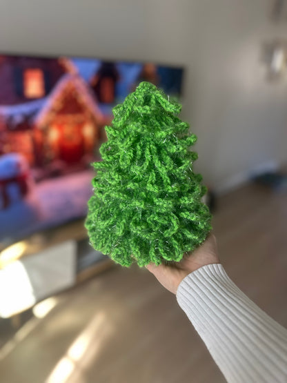 Glittery green crochet Christmas tree made from sparkly yarn, placed on wooden furniture

