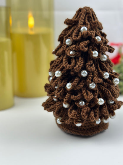 Brown crocheted Christmas tree ornament, Christmas tree with silver beads on a white surface.