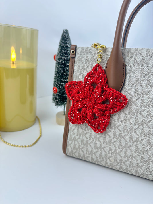 Handmade crochet star keychain in soft pastel yarn with metal clasp, displayed as a cute holiday accessory