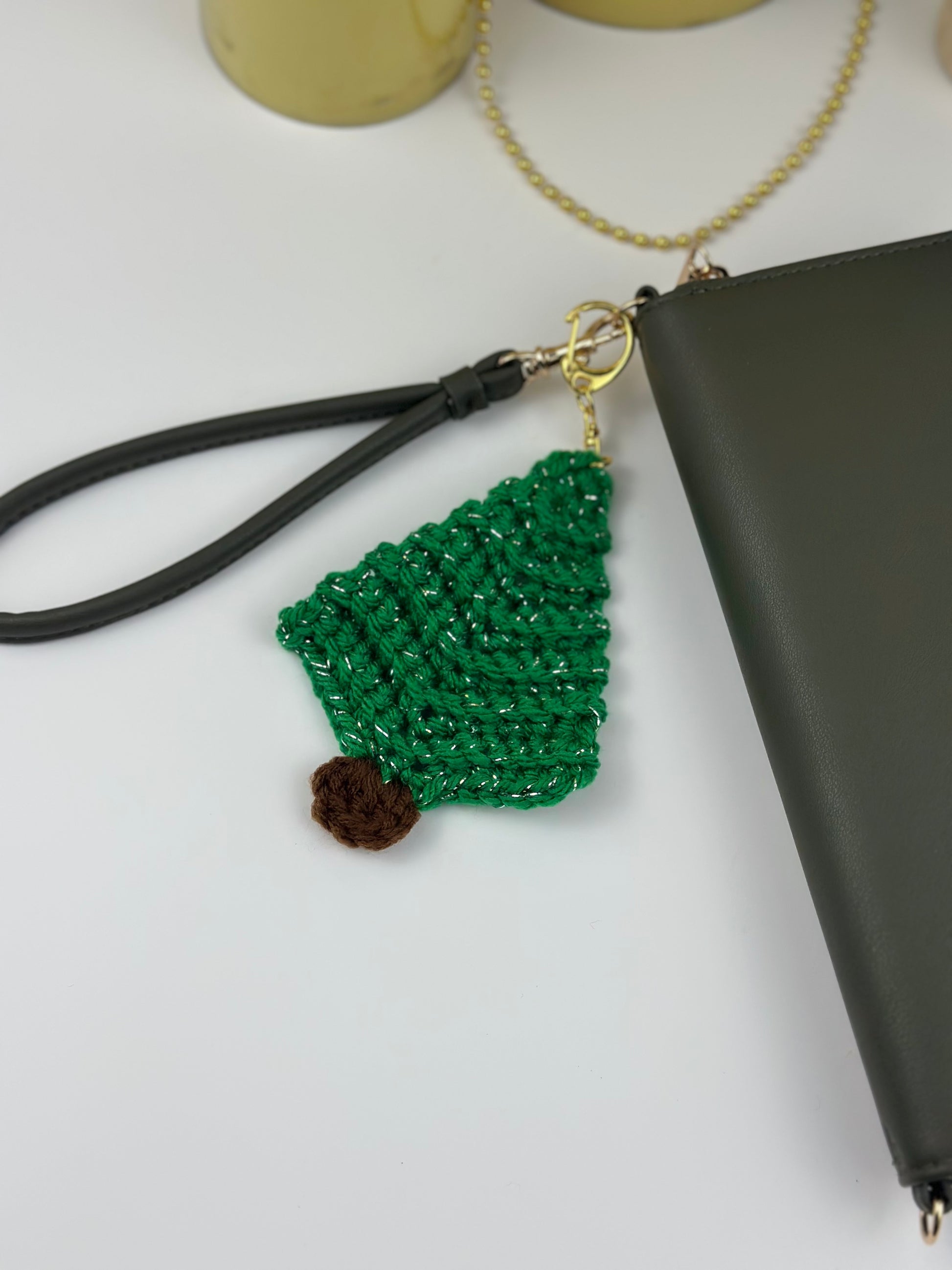 Crochet holiday keychain shaped like a green tree with glittery yarn details