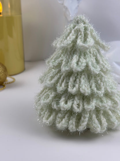 Soft white crochet Christmas tree displayed beside golden candles.