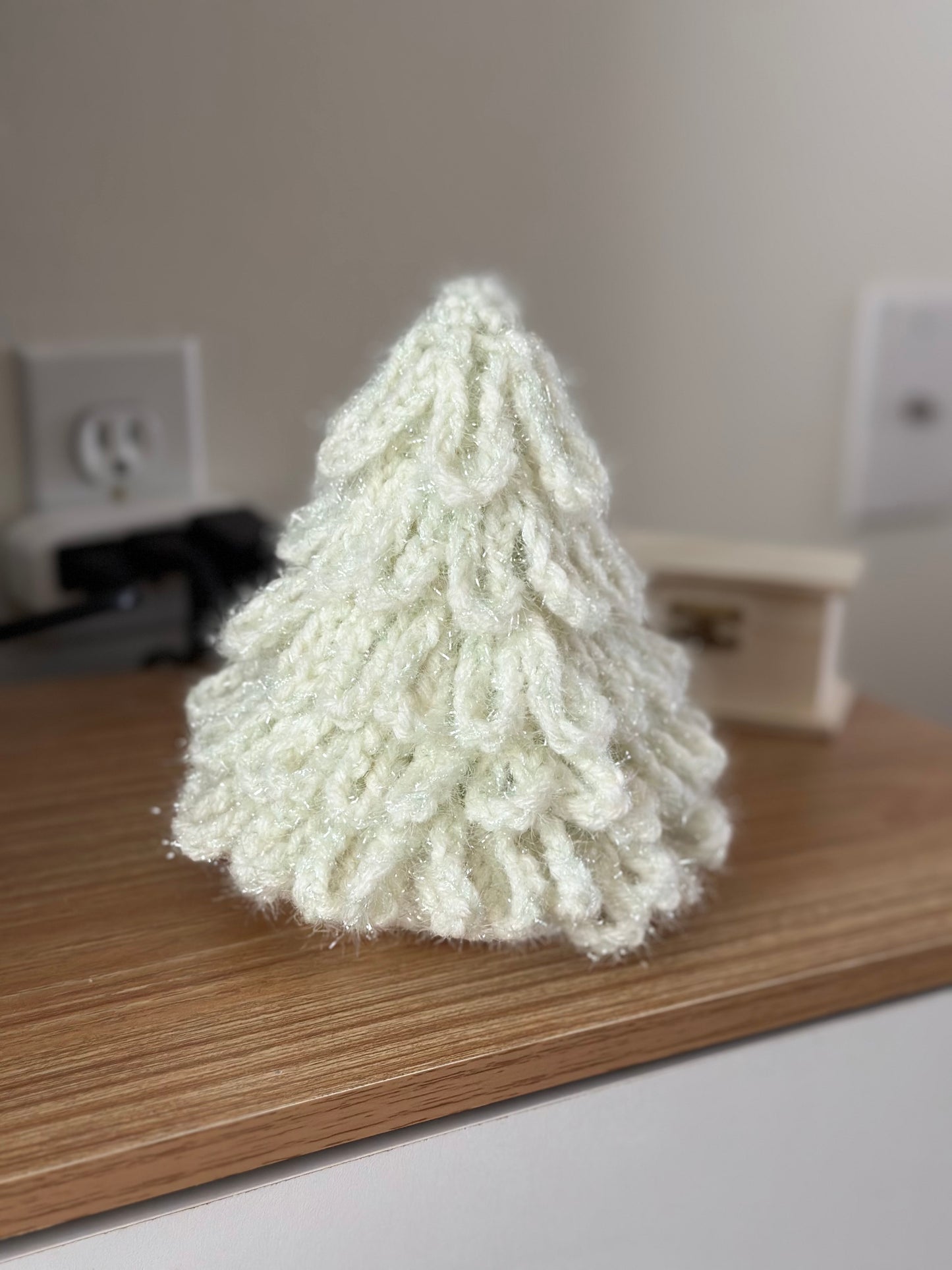Hand-crocheted Christmas tree in creamy white color on wooden table.