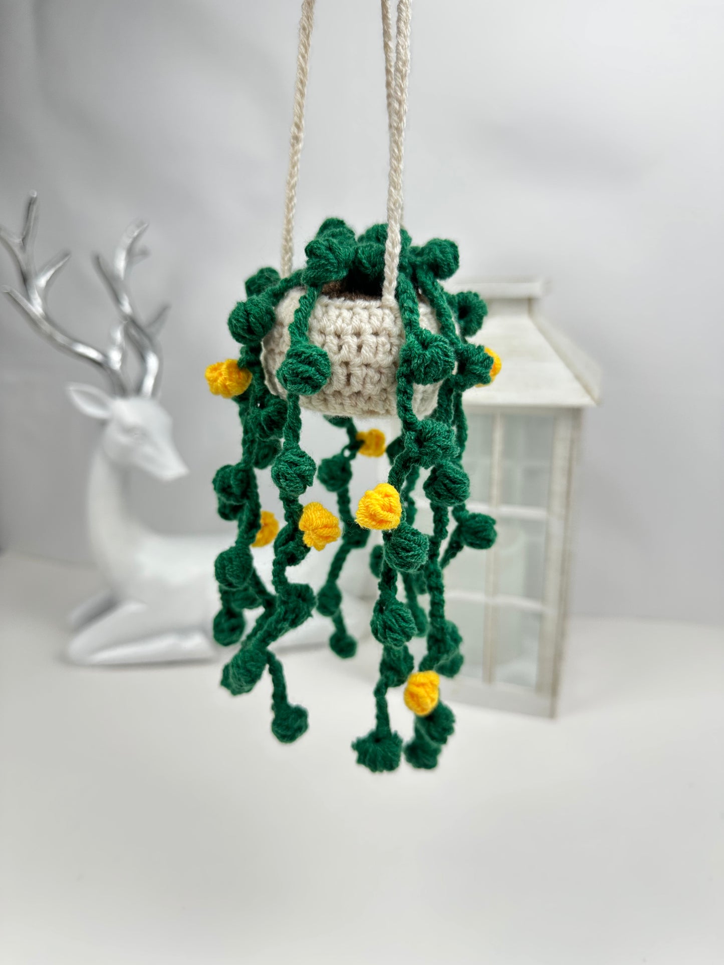 Crocheted plant with green leaves and yellow flowers on a white background, crochet kit string of pearls
