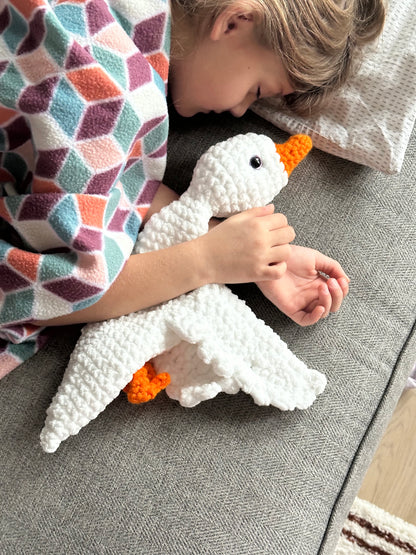 Handmade crochet comfort goose plush laying on a child’s bed