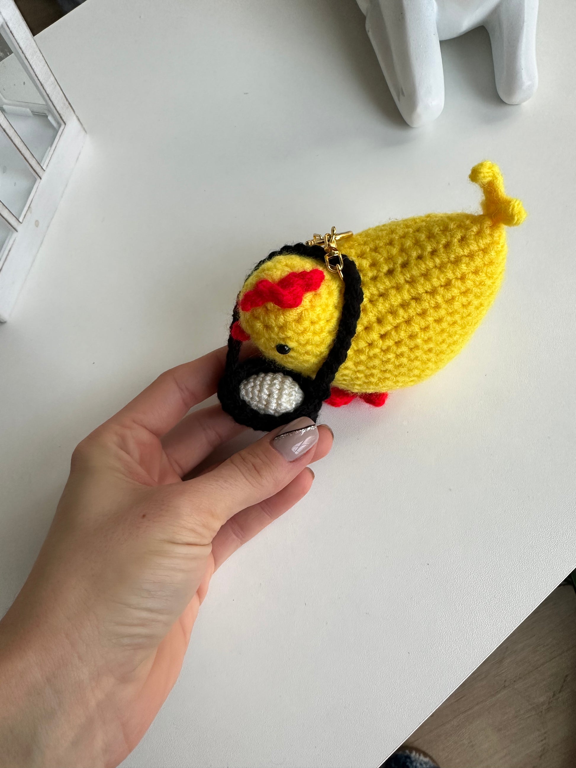 Mini crochet chicken keychain with small egg held in hand to show size