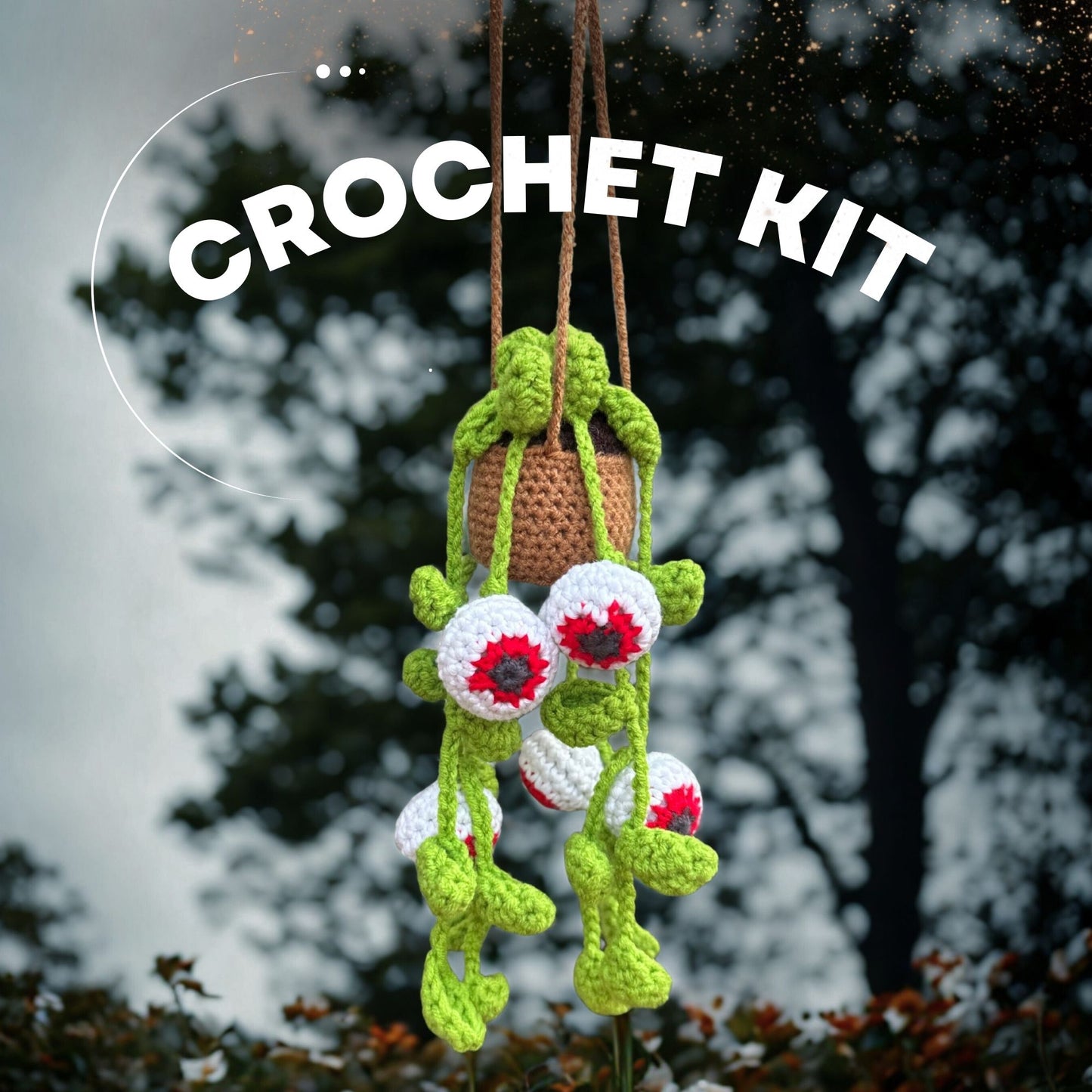 Spooky Eyes crochet plant kit hanging outdoors with dramatic cloudy background – handmade Halloween-themed yarn decor