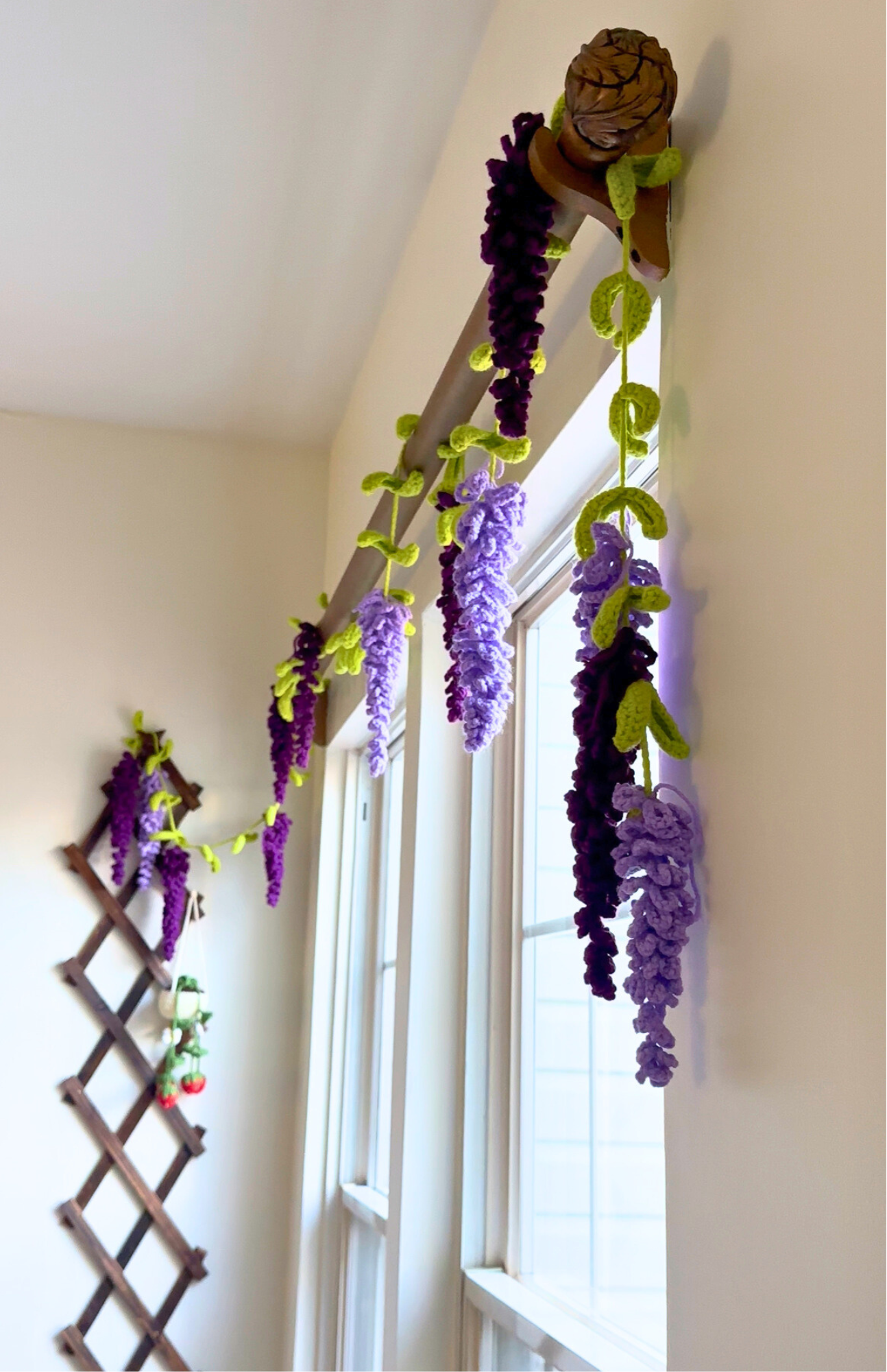 Decorative wisteria plant on a wooden trellis against a white wall.