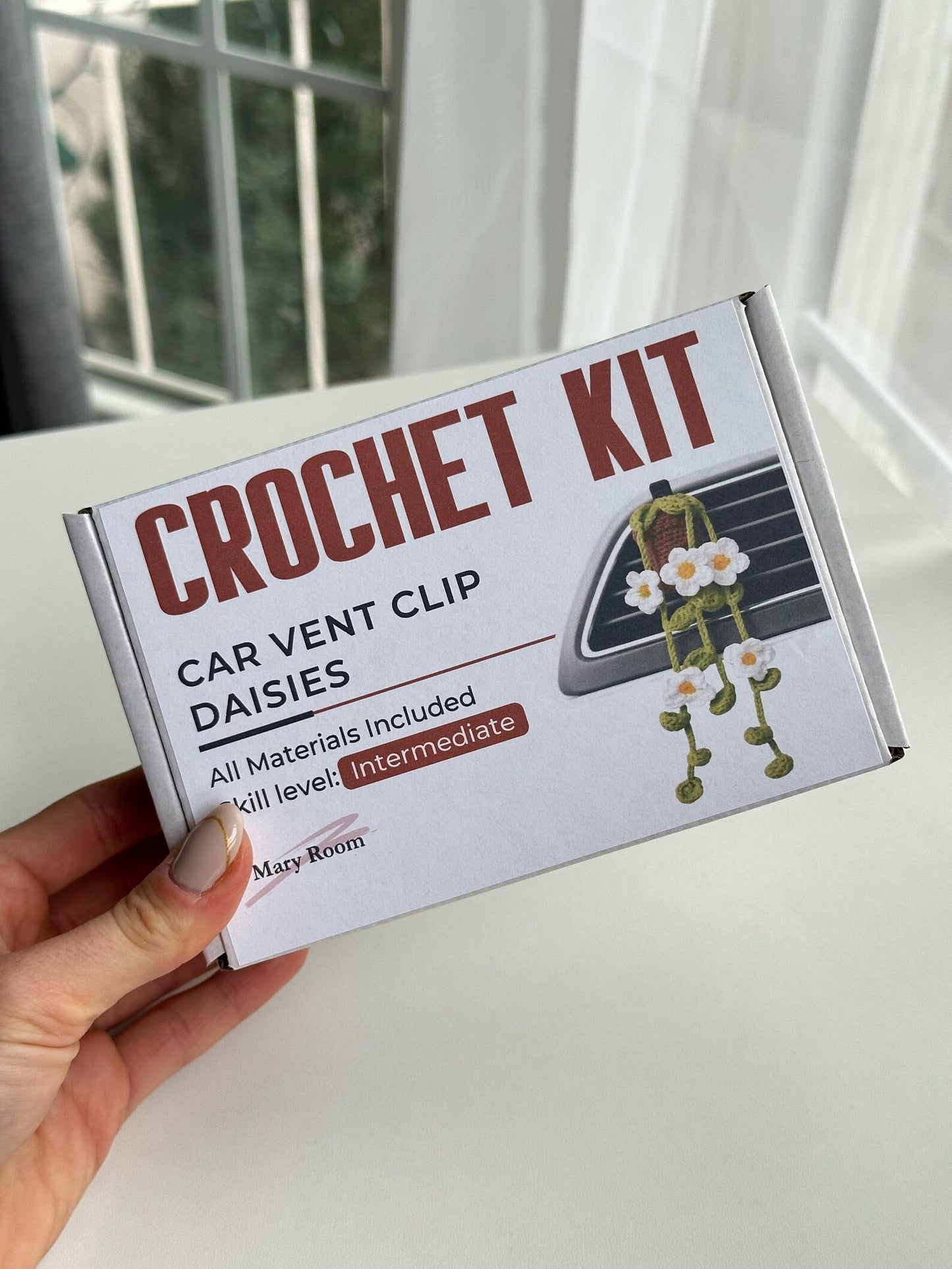 Complete crochet kit components displayed on white background: yarn, pattern card, sachet, hook, and accessories