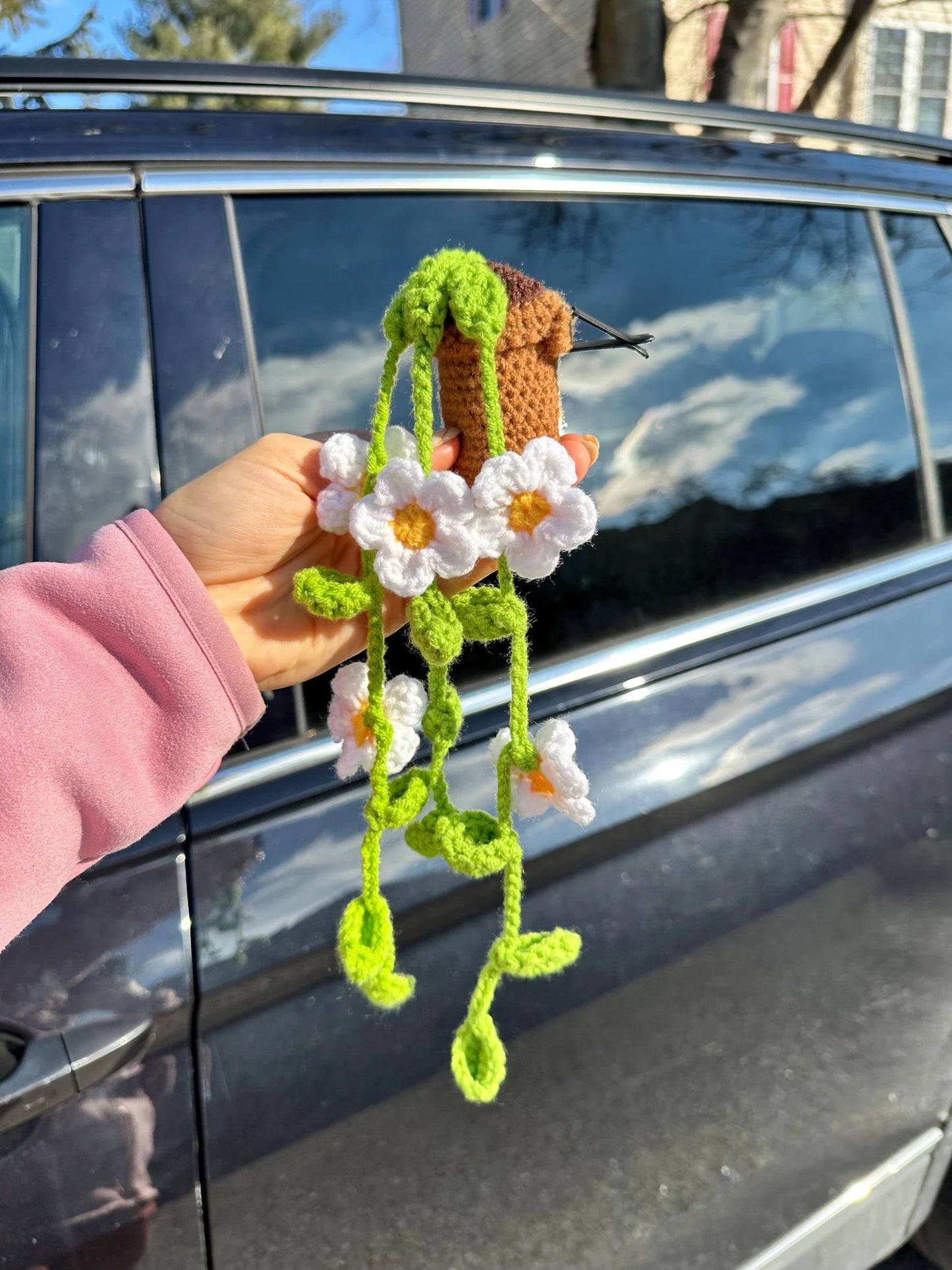 Crocheted daisy clip held in front of car door – side view. crochet kit with daisy