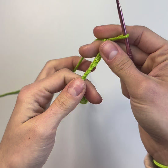 Hands crocheting green yarn stem from DIY Crochet Kit Red Bells Plant – in-progress video thumbnail.